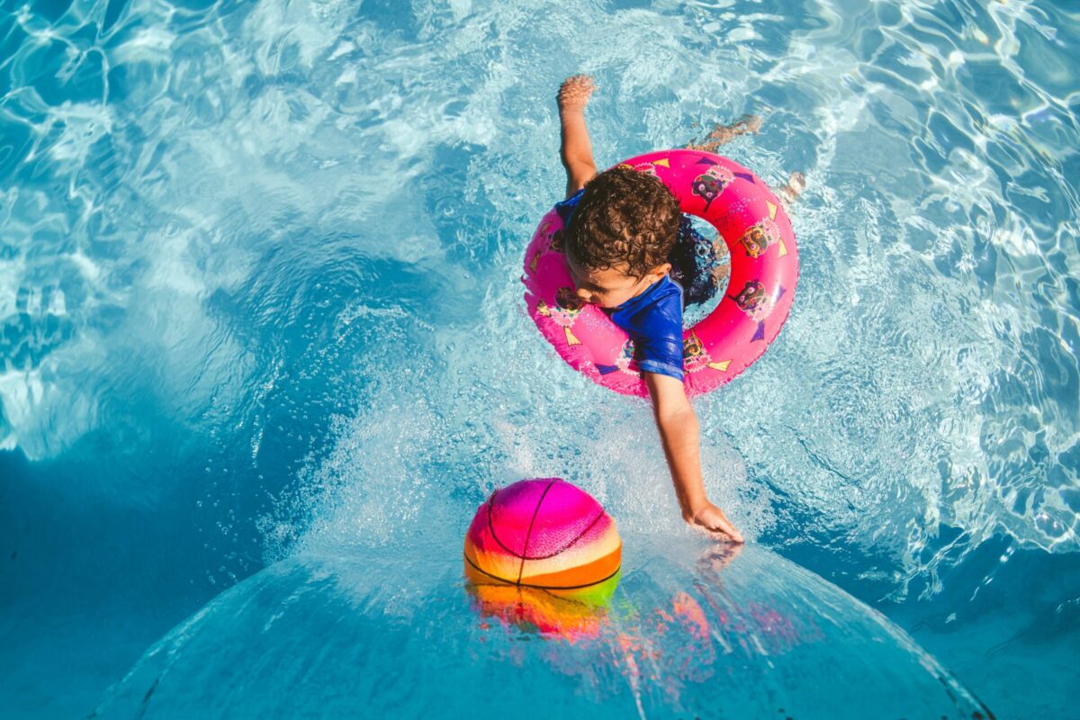 Jeune enfant dans la piscine avec ballon coloré